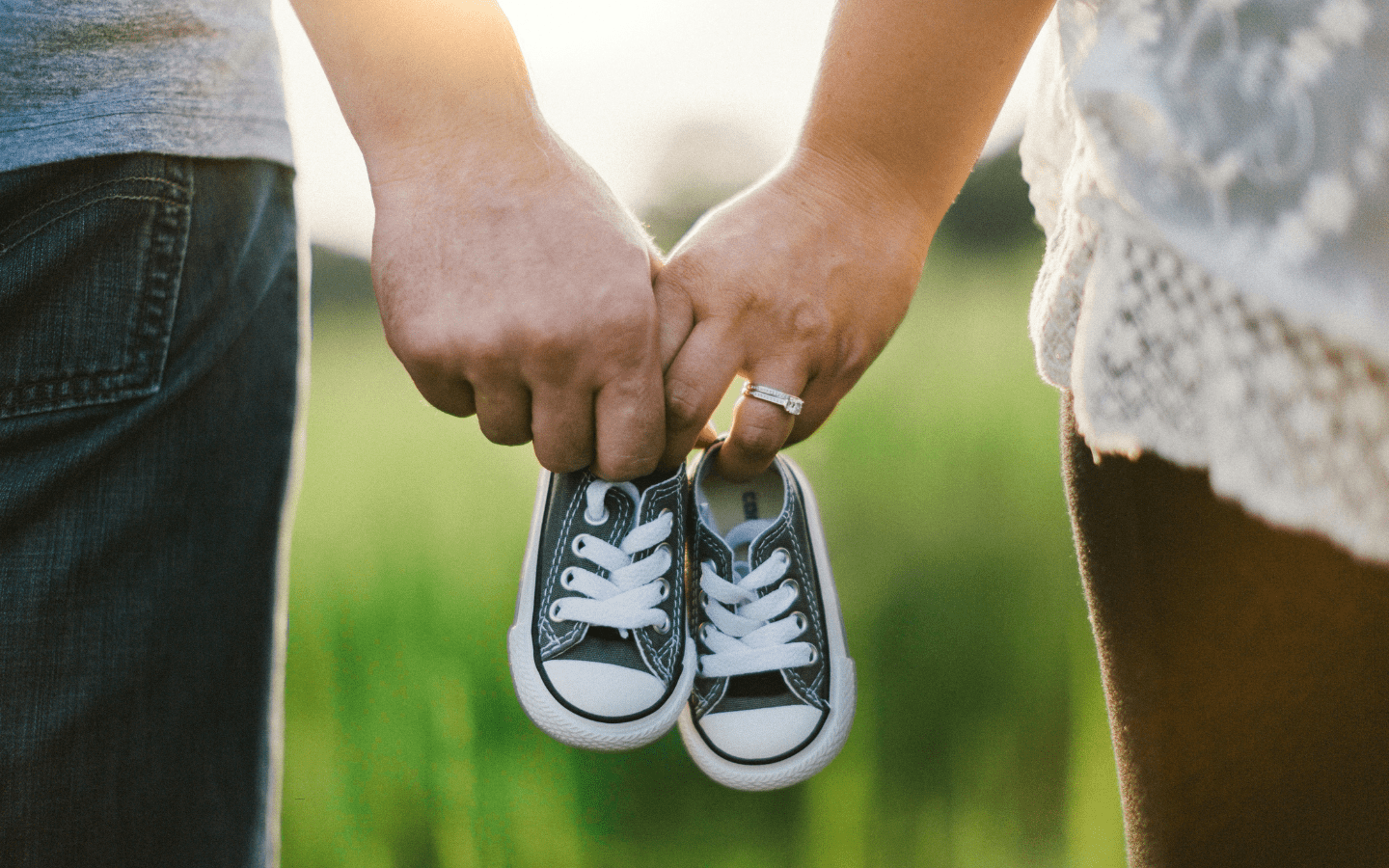 A photo of a couple holding a pair of baby shoes together.