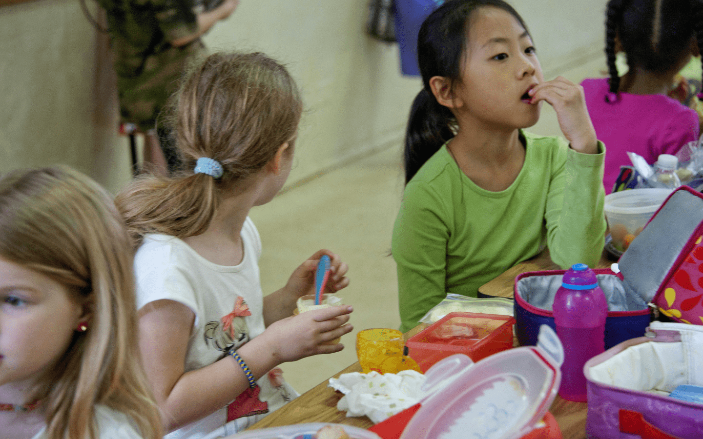 A photo of young girls eating in a school cafeteria.