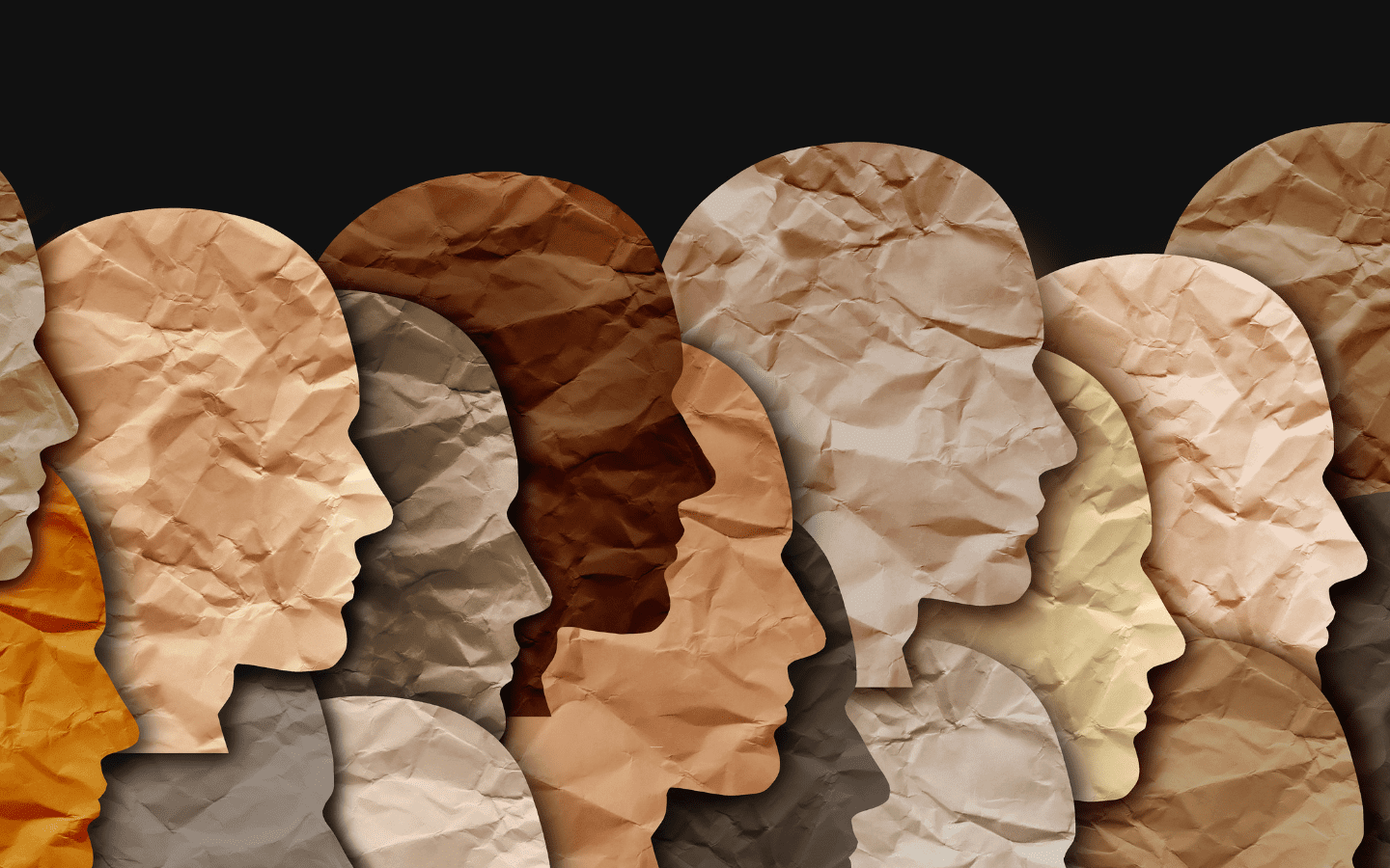 Paper cutouts depicting blank human heads of different shades.