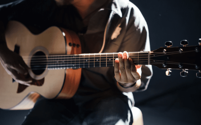 Acoustic guitar player in pale light