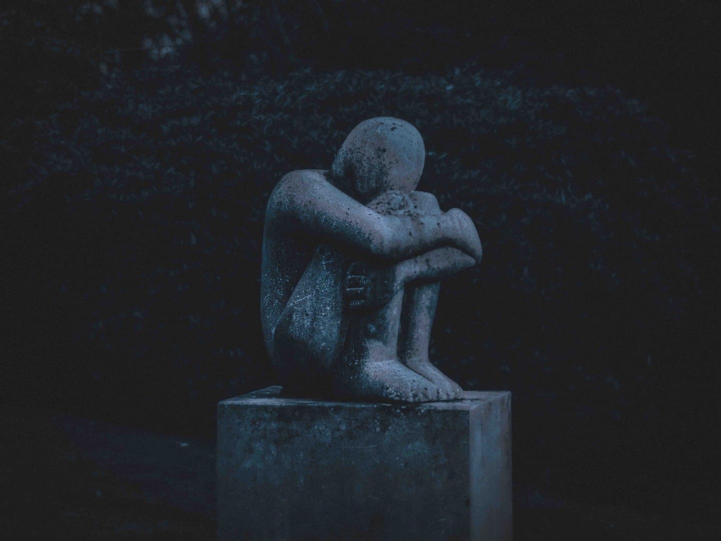 A stone figure of a person in grief.