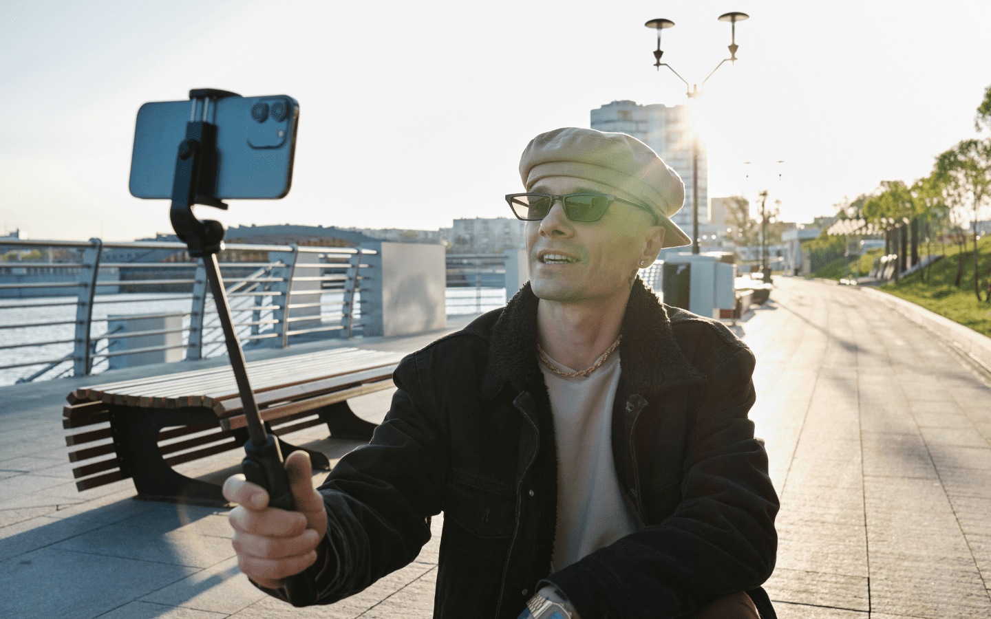 A photo of a man making a phone video with a selfie stick.