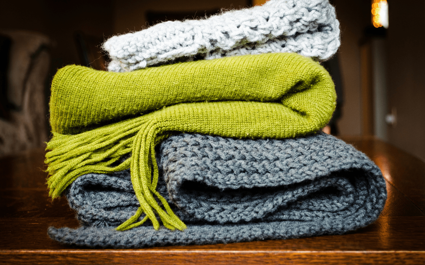 Knit scarves and shawls folded and stacked on top of each other.