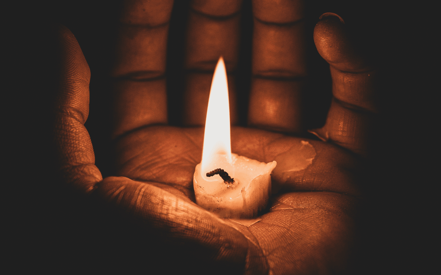 A hand holding a candle in its palm.