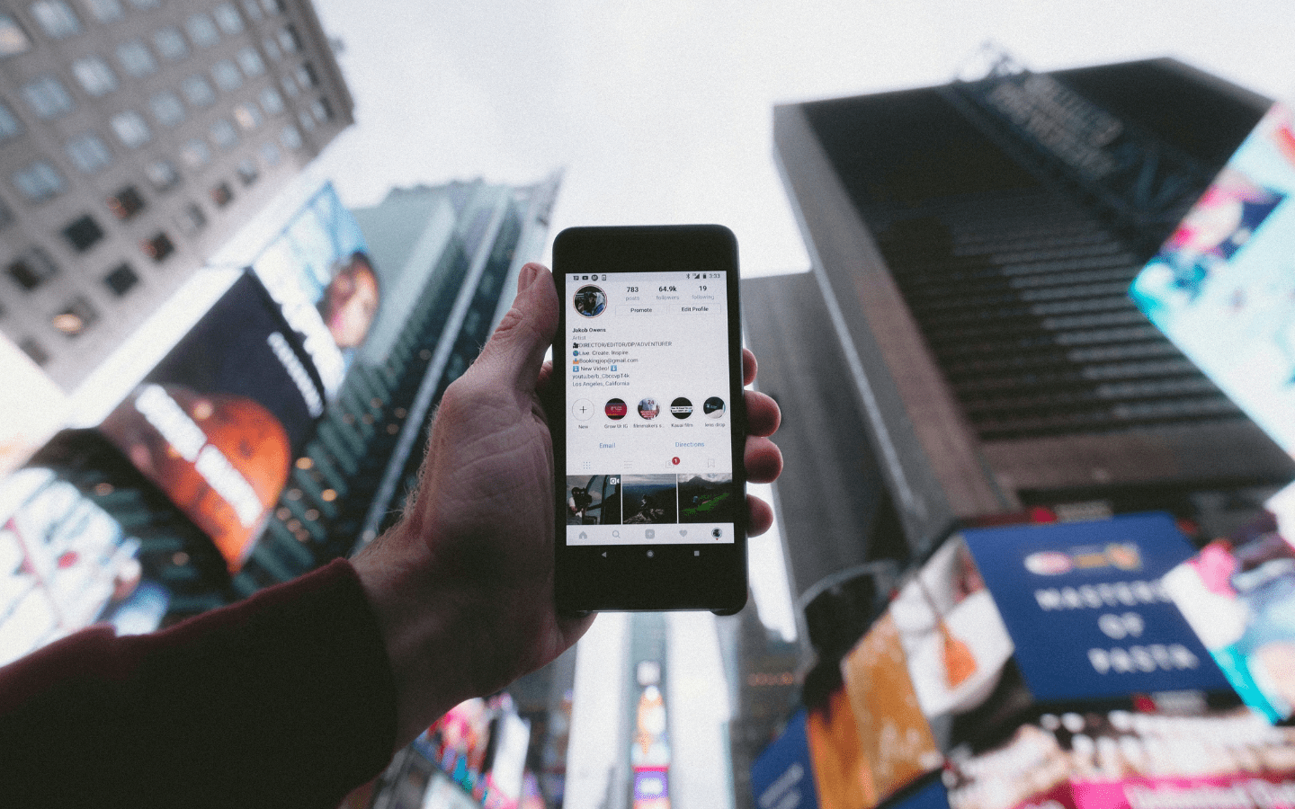 The person is holding a handheld smartphone in a busy city square.