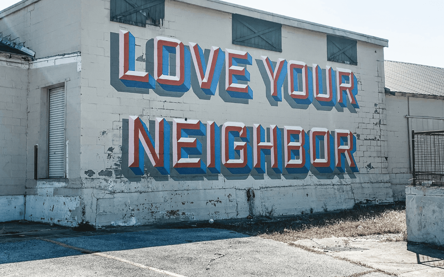 An old building with a mural reading “Love Your Neighbor”