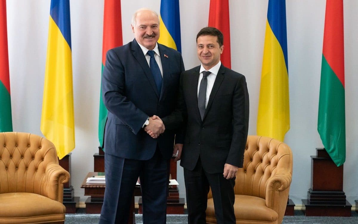 Belarusian President Oleksandr Lukashenko and Ukrainian President Volodymyr Zelensky standing next to each other shaking hands.