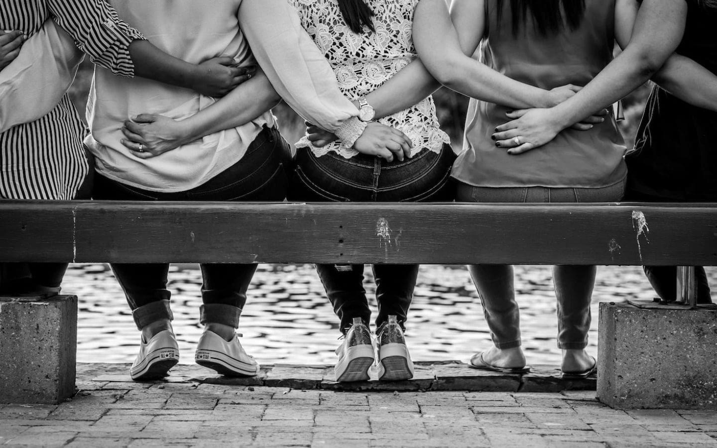 Women seated on a bench with their backs facing the camera.