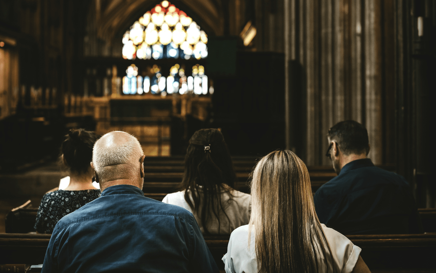 A view from behind of worshippers sitting in a pew.