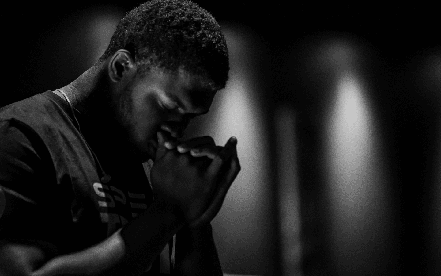 A black and white photo of a man praying.|