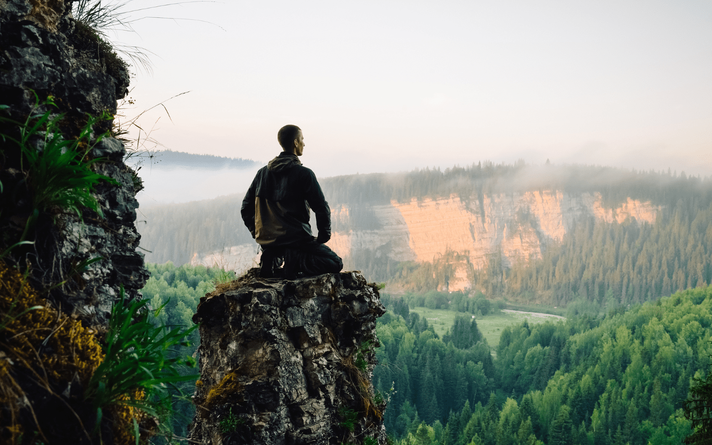 A man on a mountain practicing mindfulness.