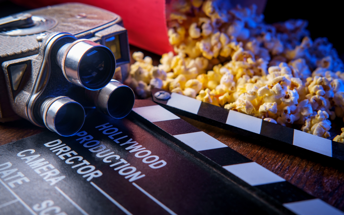 A director’s board, projector, and movie popcorn placed next to each other.