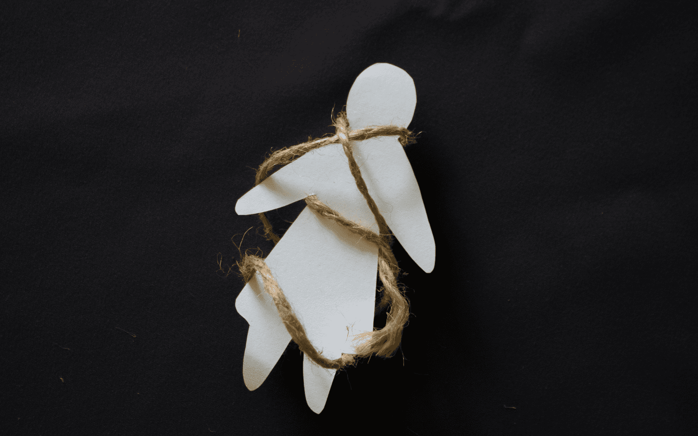 A paper doll tied up with twine.