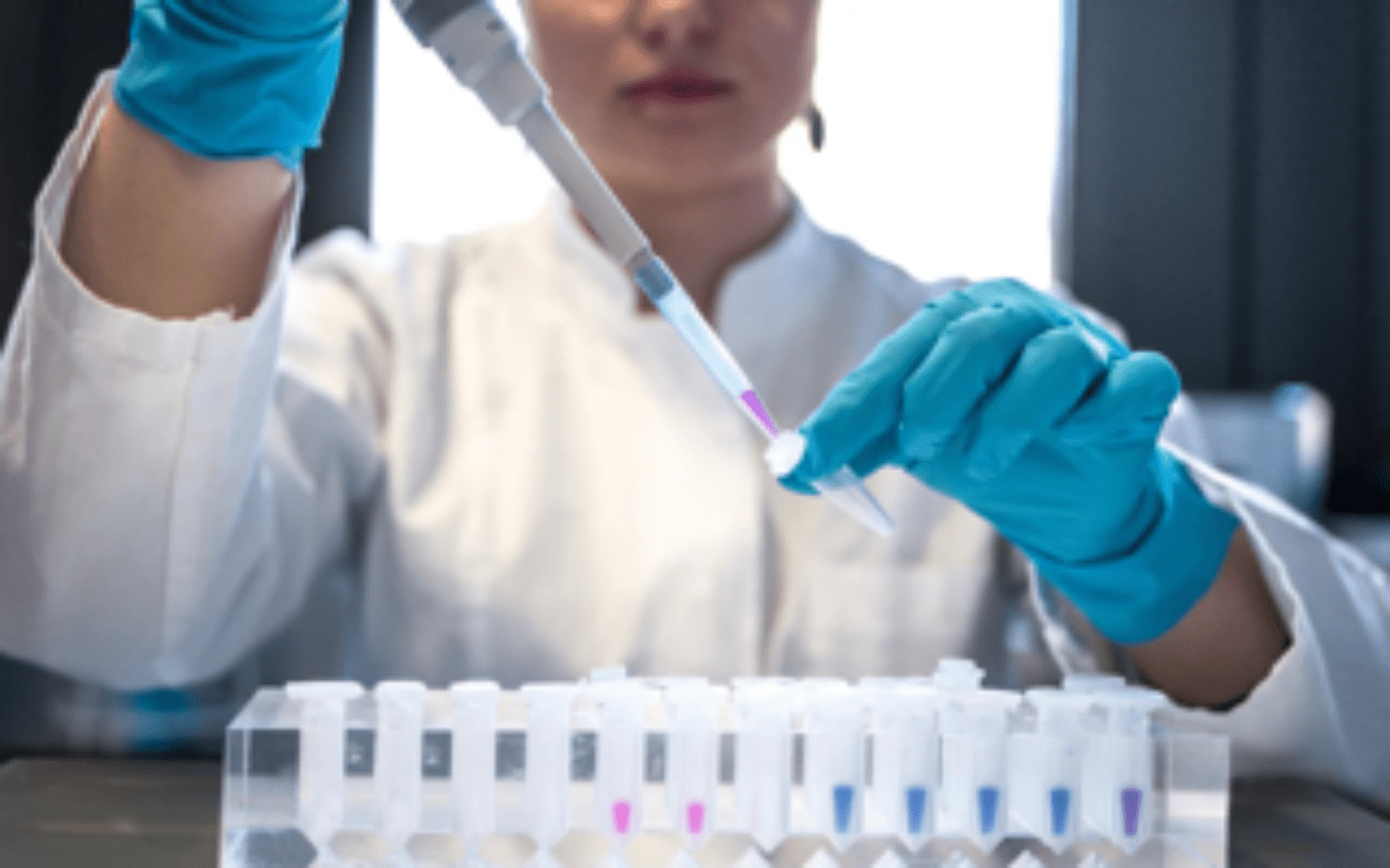 A female scientist pipetting chemicals into a tube.