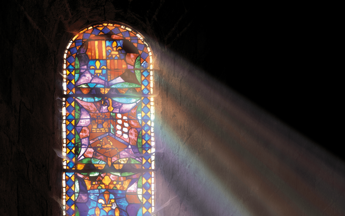 A photo of a stained glass window with the sun shining through.