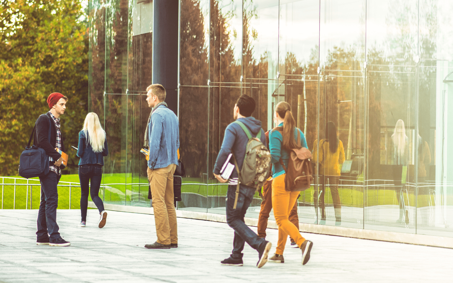 Students walk in front of a modern glass building.