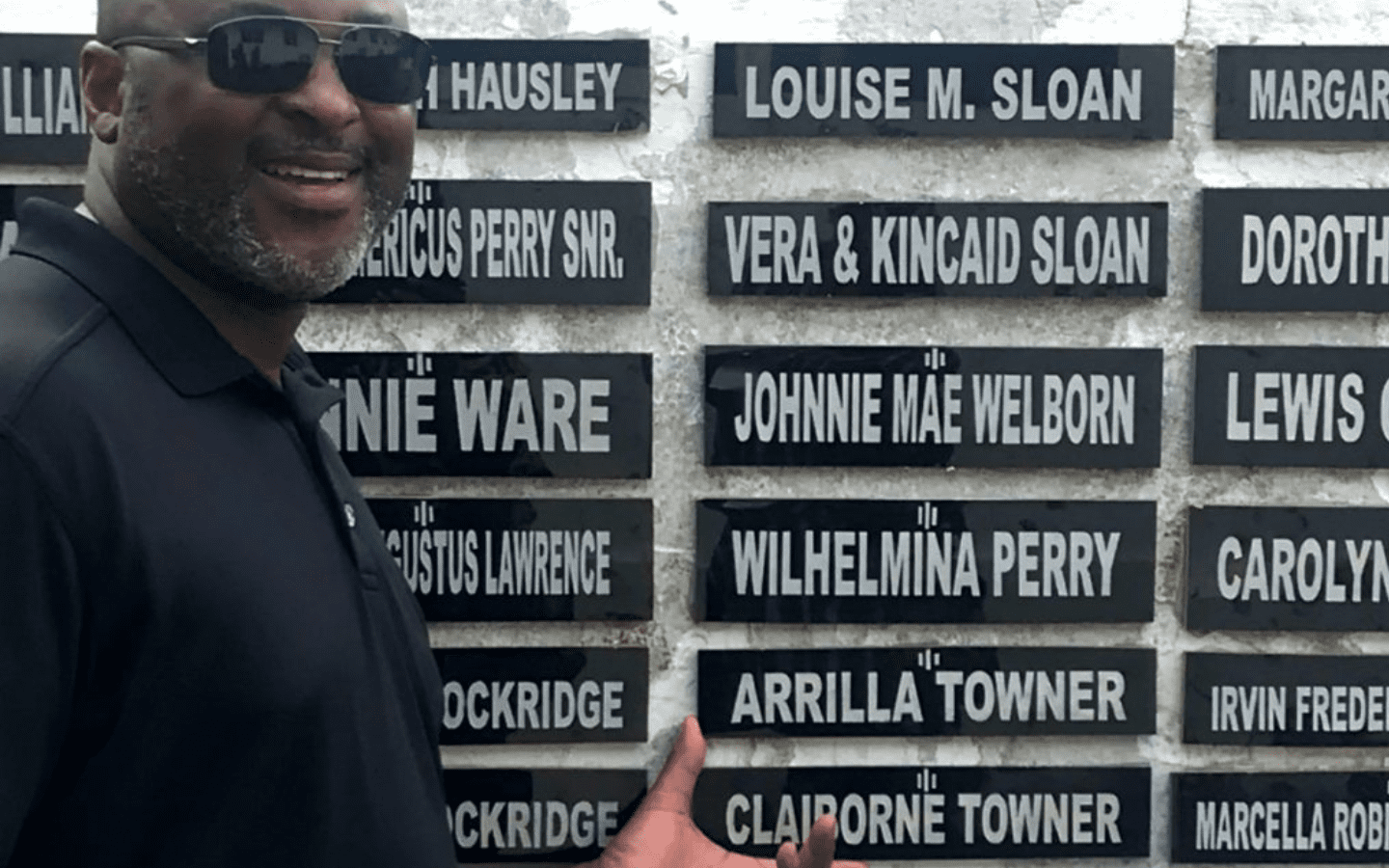 A photo of Andre Towner in front of a memorial with nameplates for Arrilla and Claiborne Towner.|