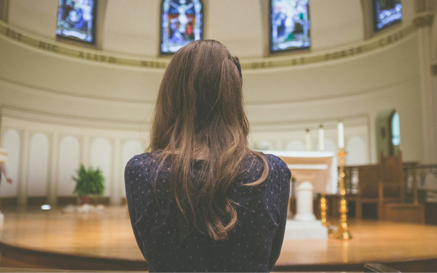 A woman stands alone at the altar in a church sanctuary.
