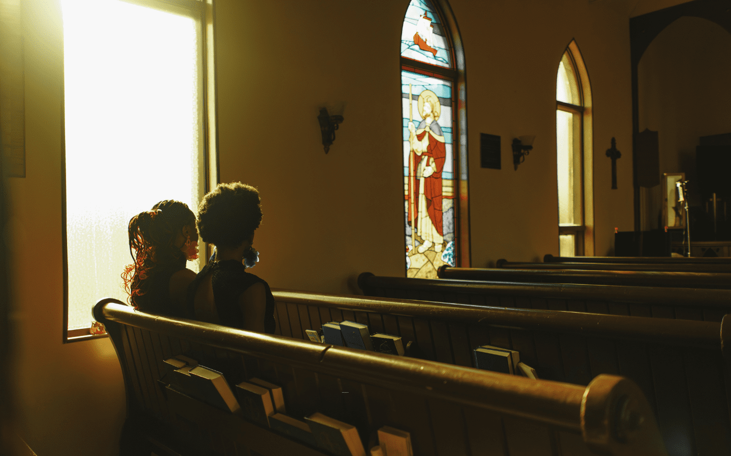 A young couple sits in pews in an empty church.|
