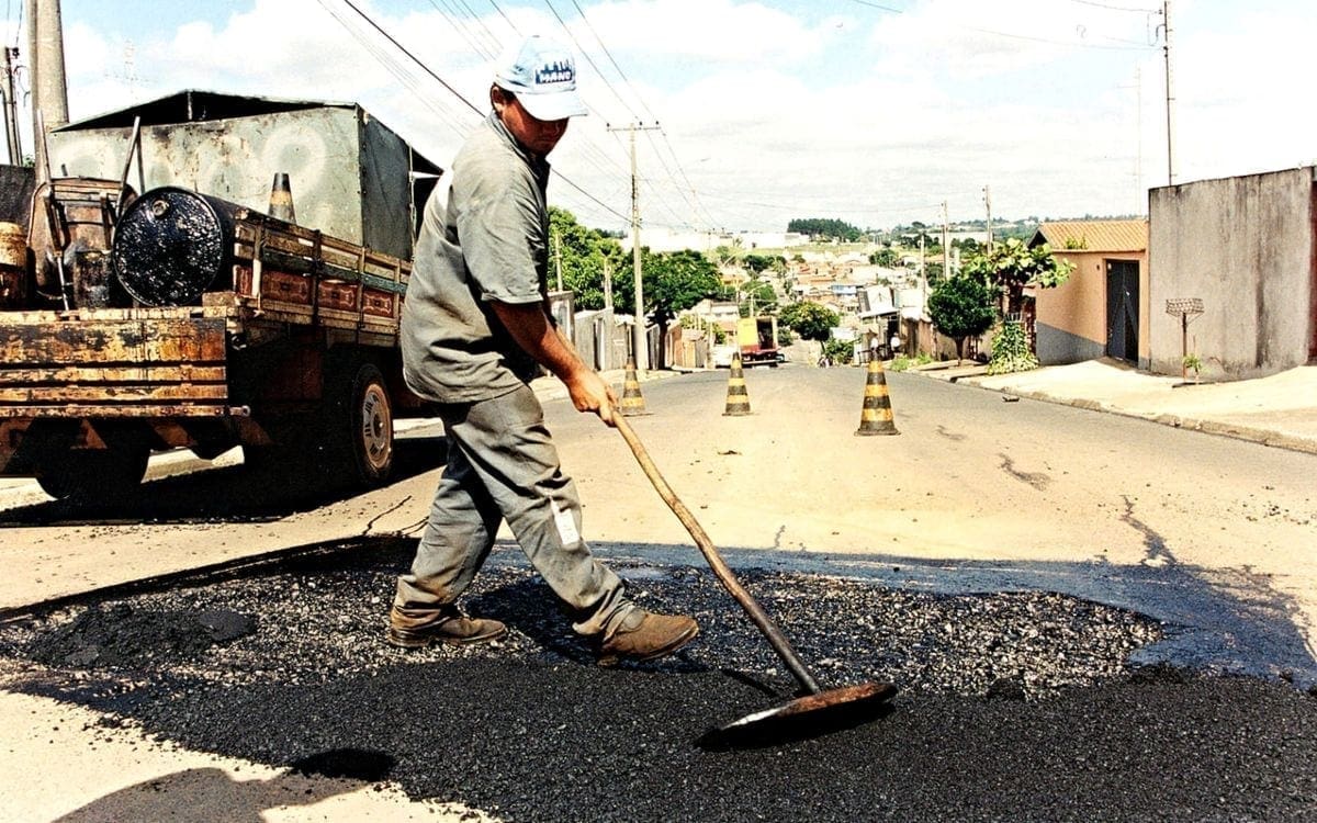 Worker spreading asphalt on road