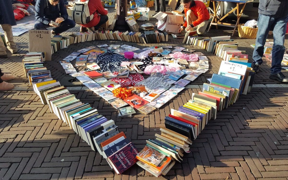 A book sale on the street with books arranged into a heart.