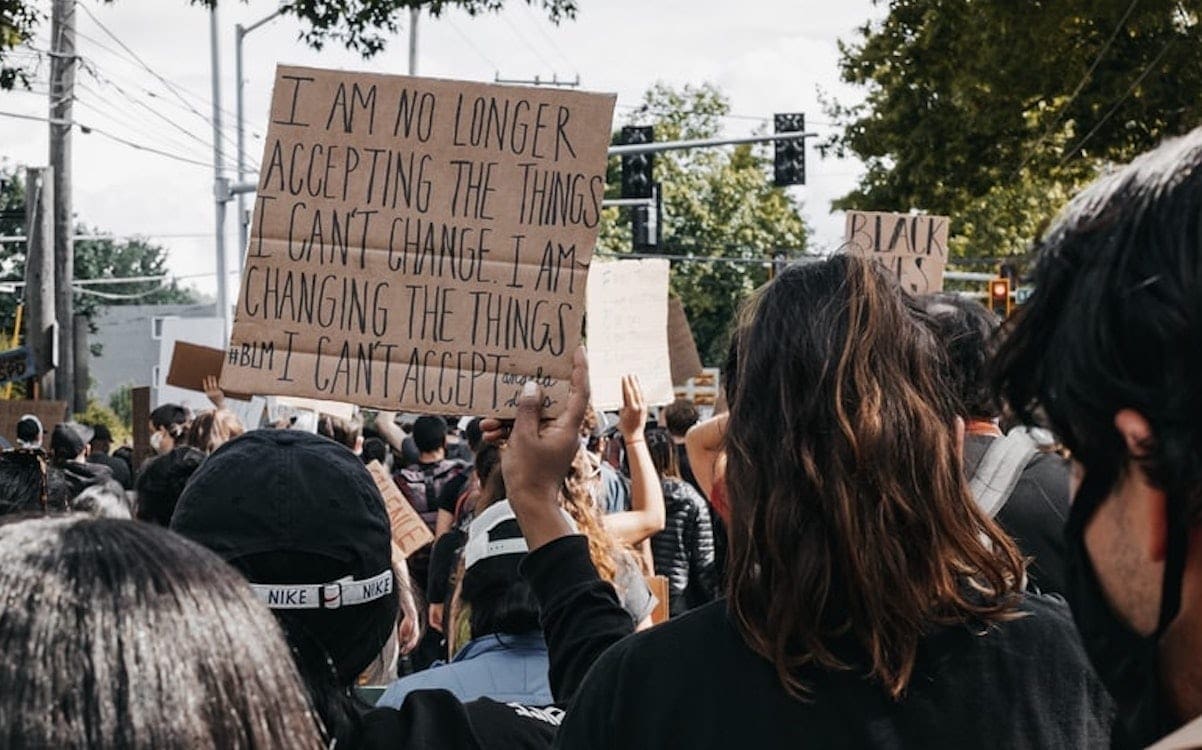 A person in a crowd of people holding a sign that says