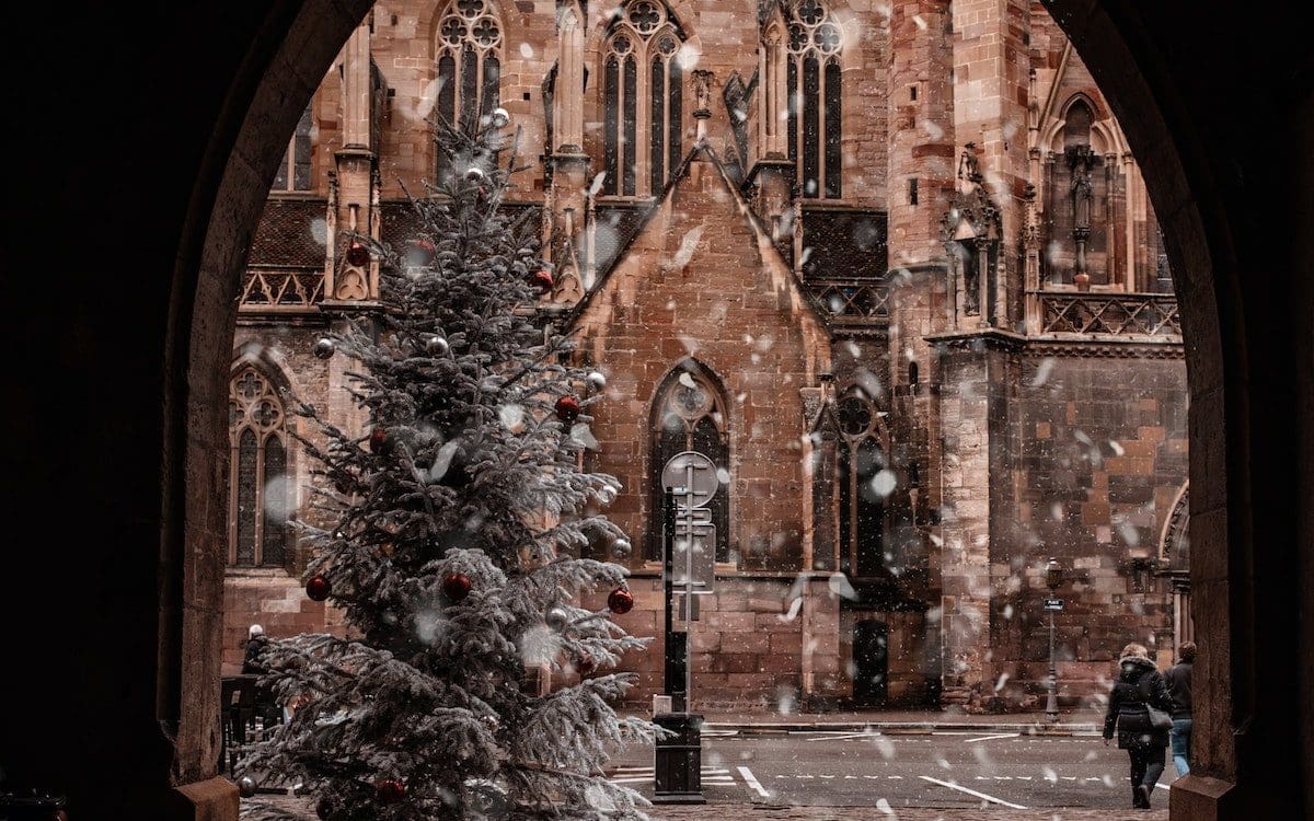 The exterior of a church with a Christmas tree outside.