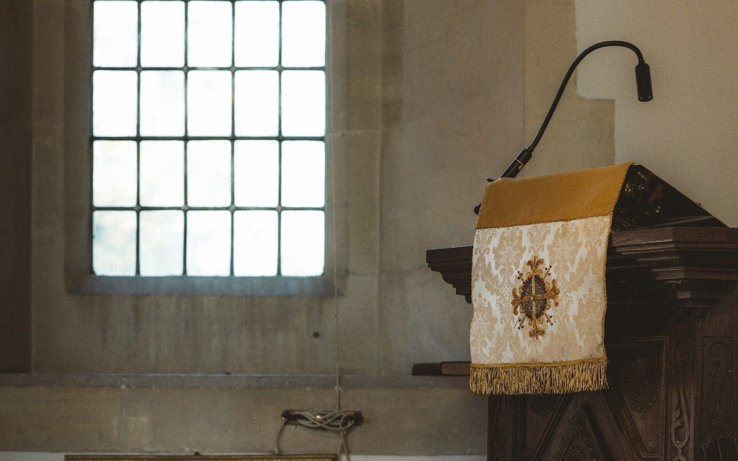 A church pulpit seen from the side with sun shining through a clear glass window next to the pulpit.|||||