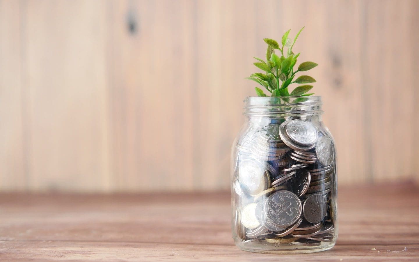 A clear glass jar filled with coins and a small