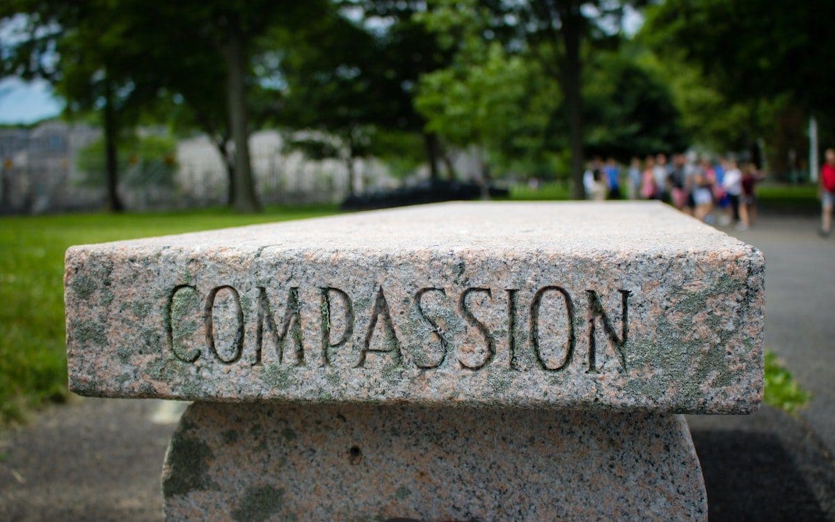 A pink granite bench with the word “compassion” etched into the side.
