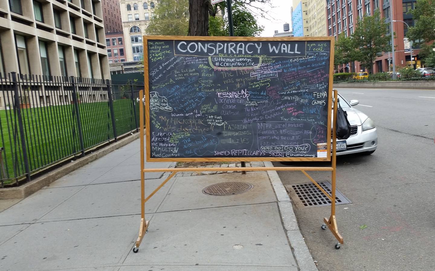 A chalkboard on the street filled with writing and with a title