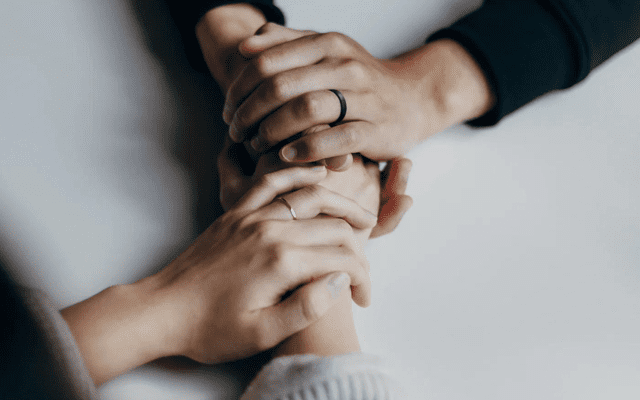 A husband and wife hold hands across from each other at a table.