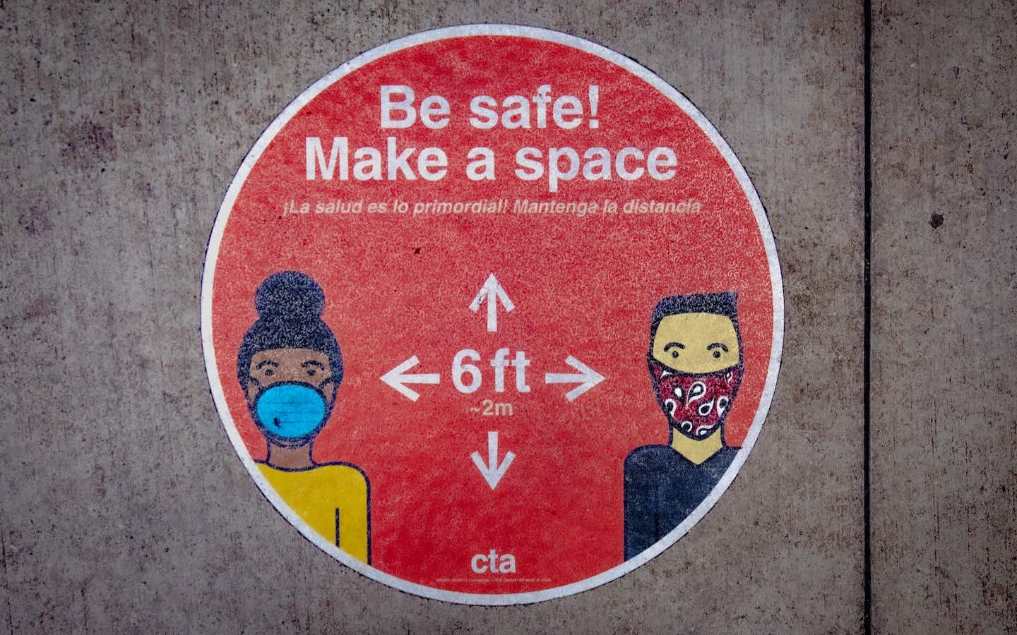 A red circle sign promoting masking and distancing during the COVID-19 pandemic.