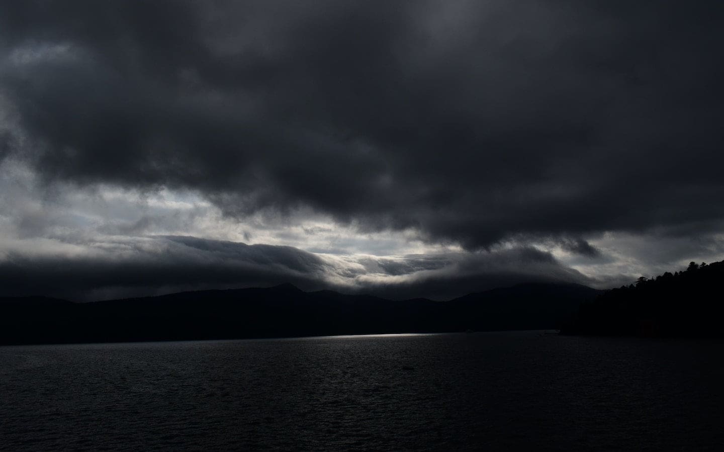 Rain clouds covering most of the sky with a small bit of sun shining through.