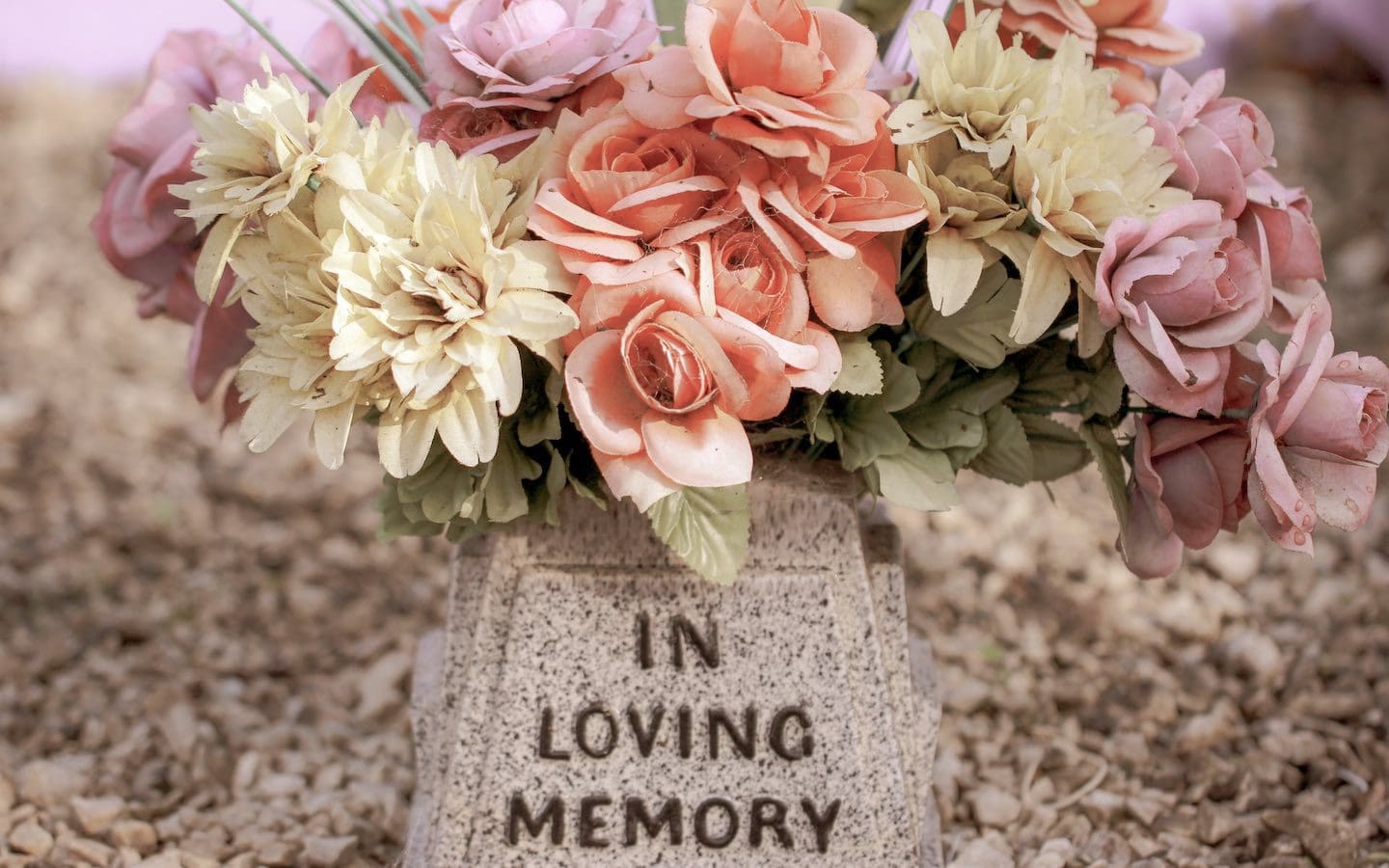 A bouquet of flowers on a gravestone inscribed with the statement