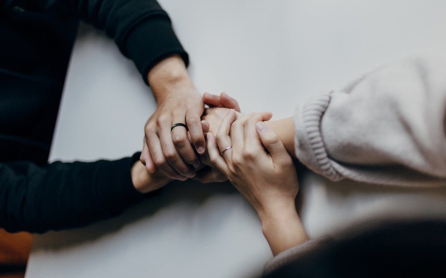 Two people holding hands across a table.