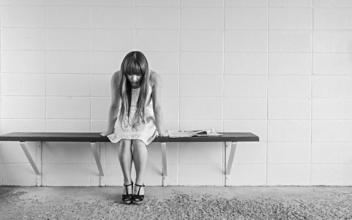 Young girl sitting alone on bench