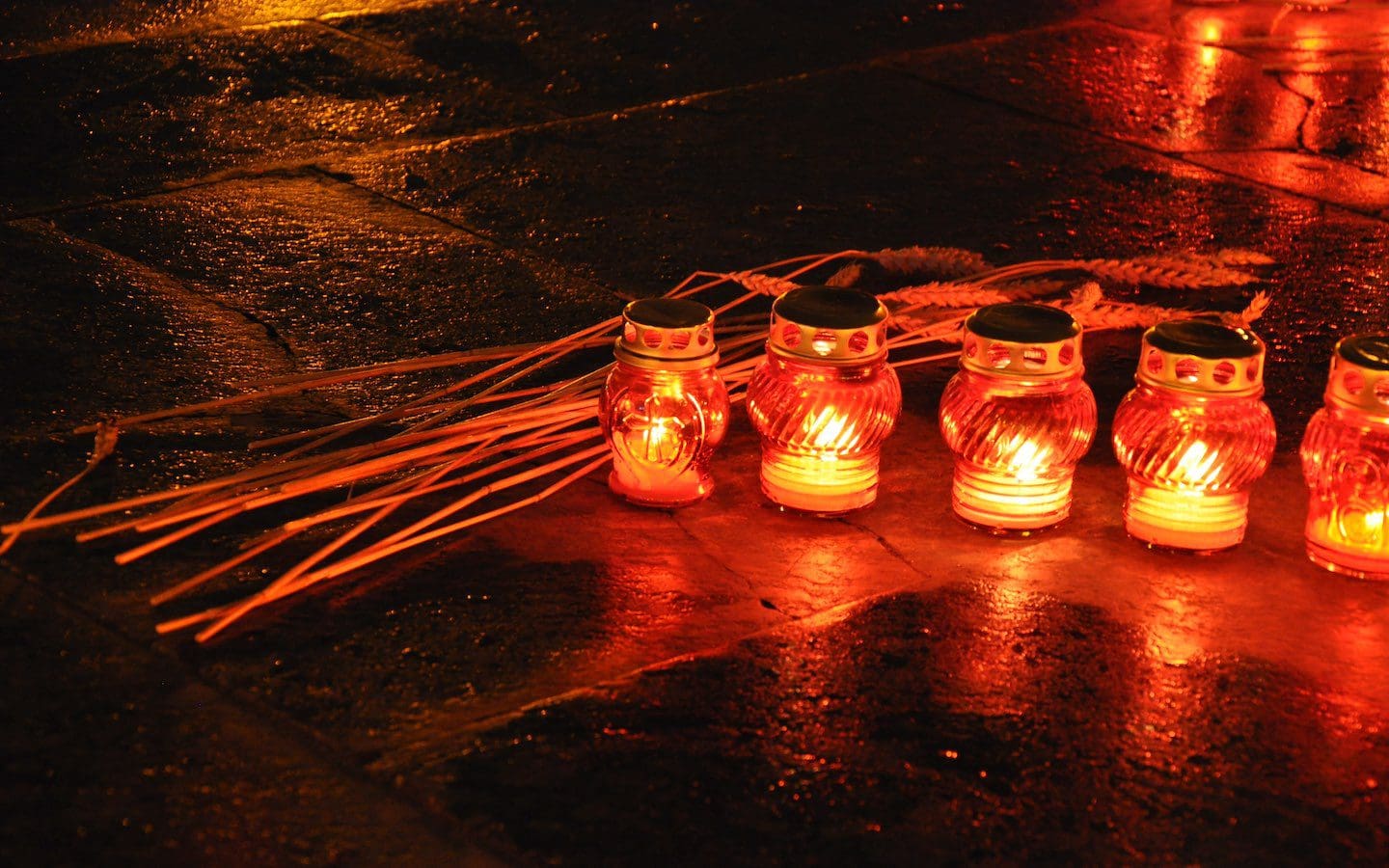 Candles and wheat sitting on a sidewalk at night as a symbol of remembrance during the Holodomor Remembrance Day 2013 in Lviv
