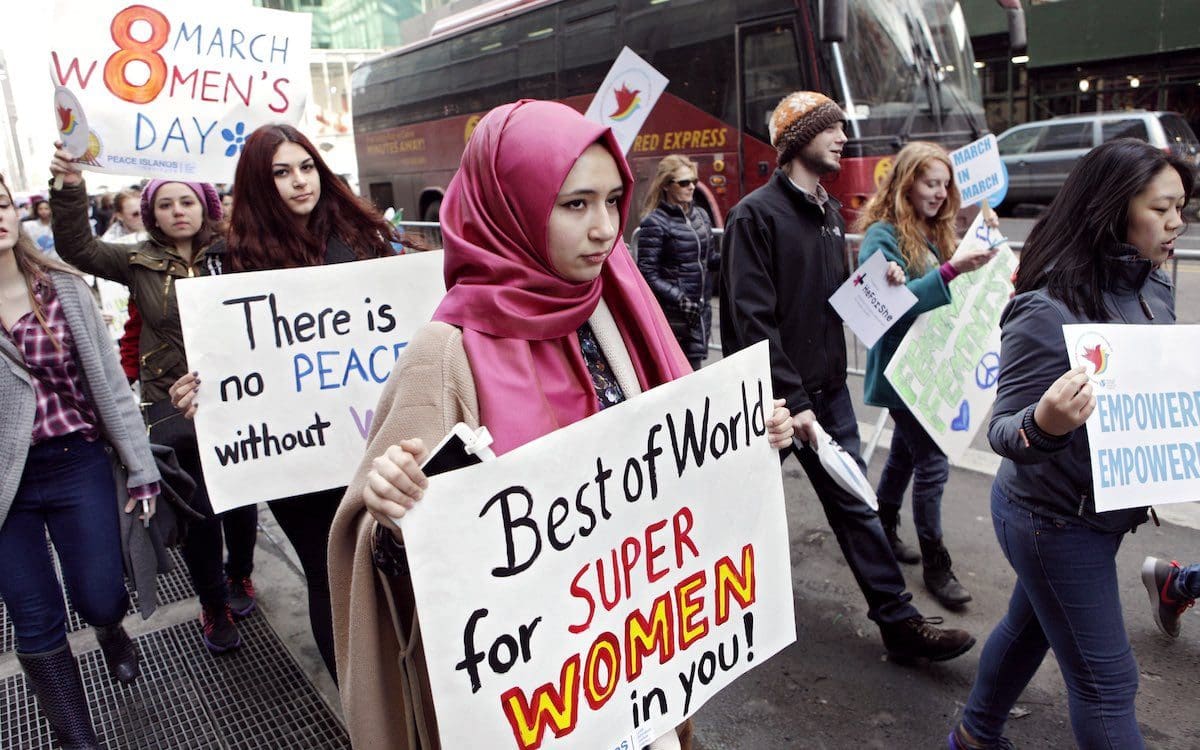 Women walking on a street holding signs as part of a march through midtown Manhattan