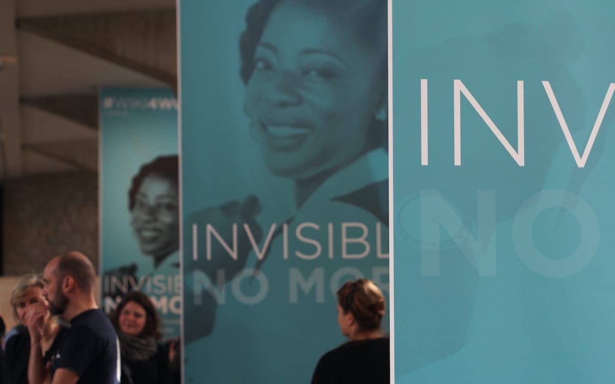 A set of blue banners that read “Invisible No More” with a woman’s face on several of them.