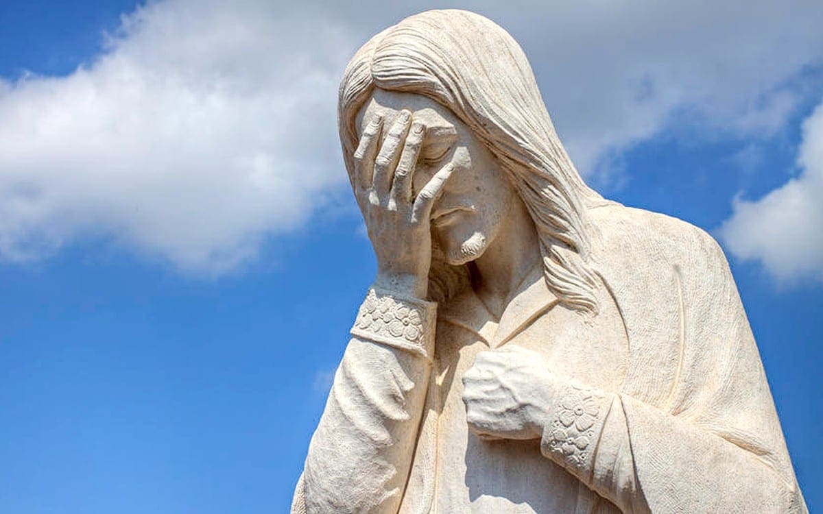 Jesus statue weeping into his hand