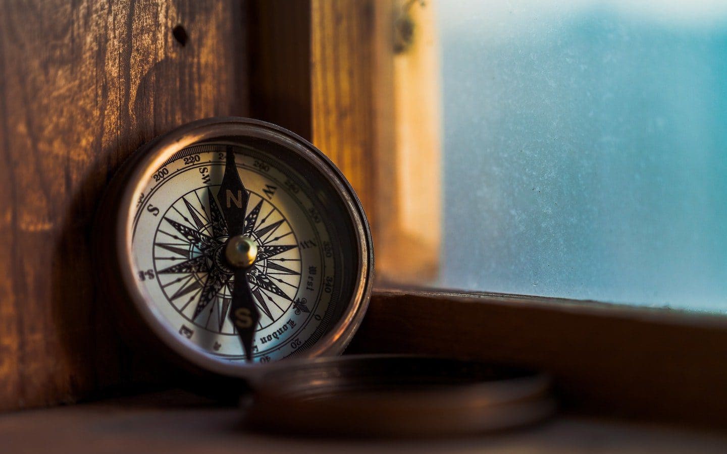 An open compass sitting next to a window.