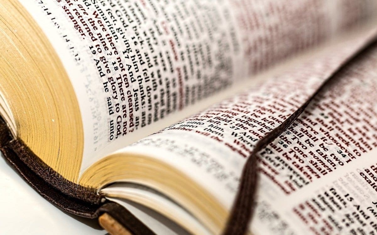 A close up image of the bottom half of an open Bible with a string bookmark.