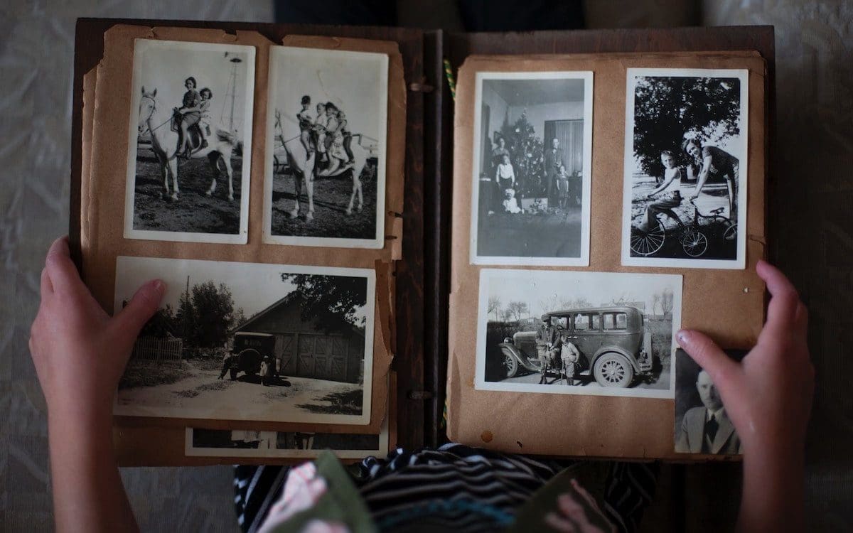 A young girl seen from above holding a book with older photos inside.