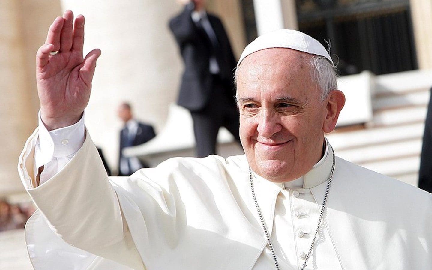 A closeup photo of Pope Francis waving to a crowd in 2016.