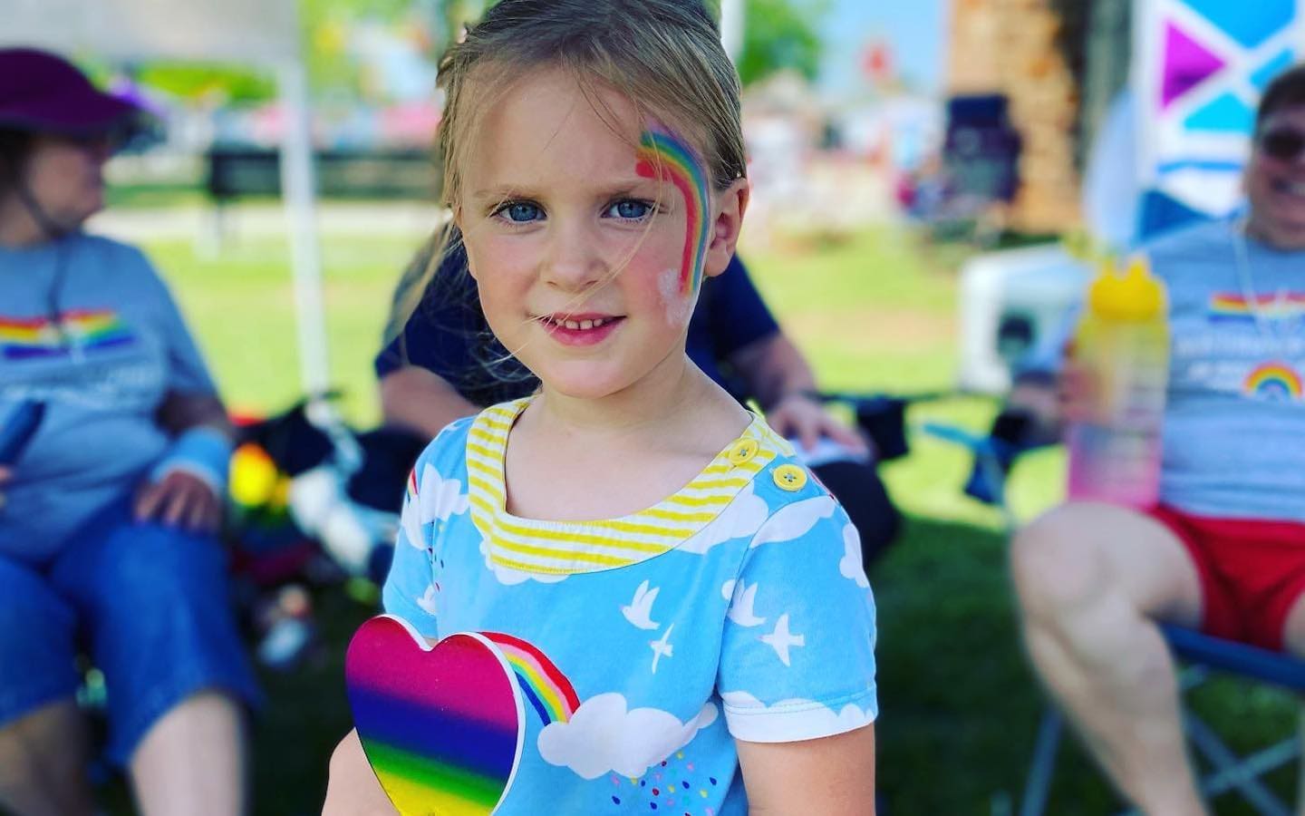 A picture of a little girl with a rainbow painted on her cheek.