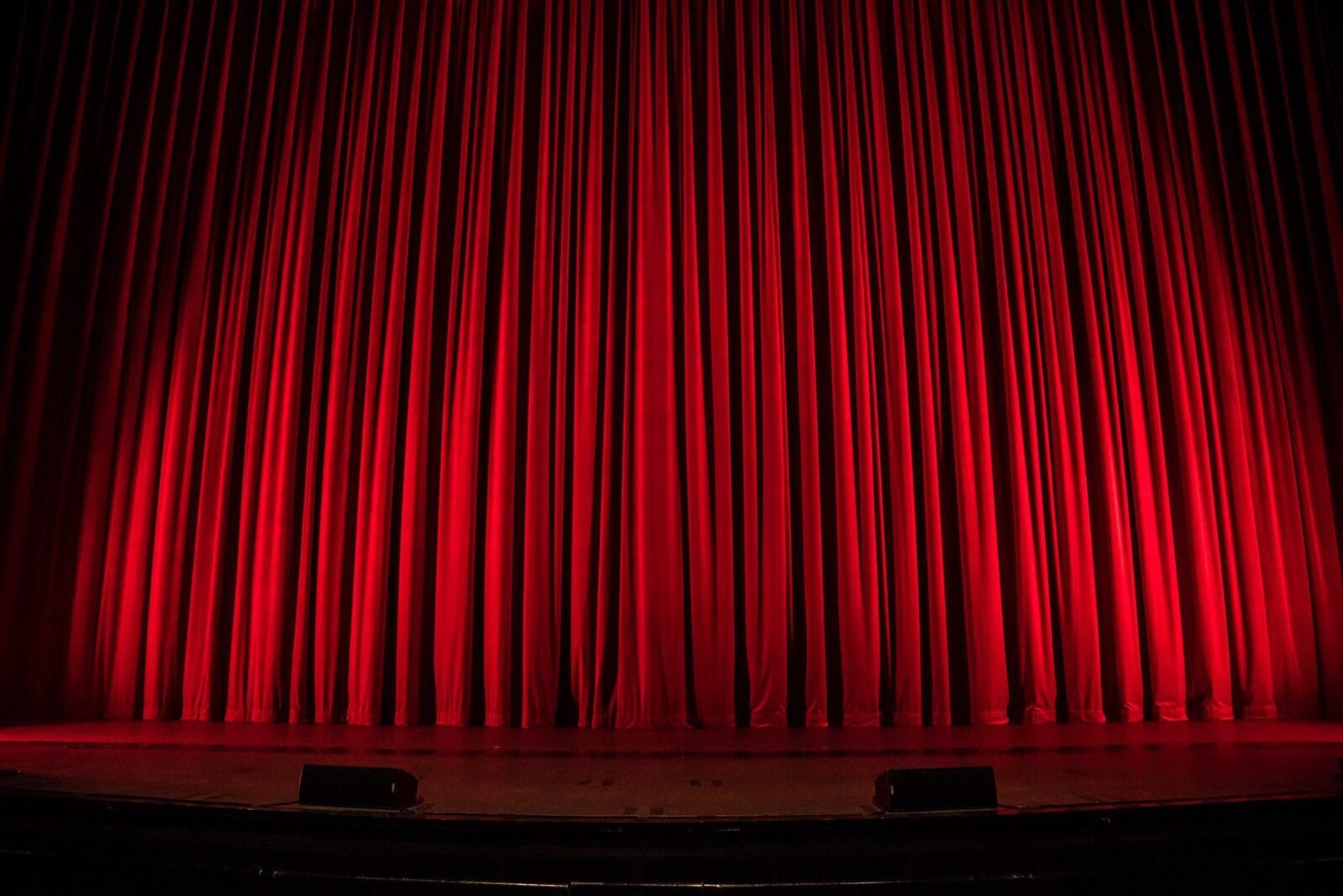 A red curtain on a large theater stage.
