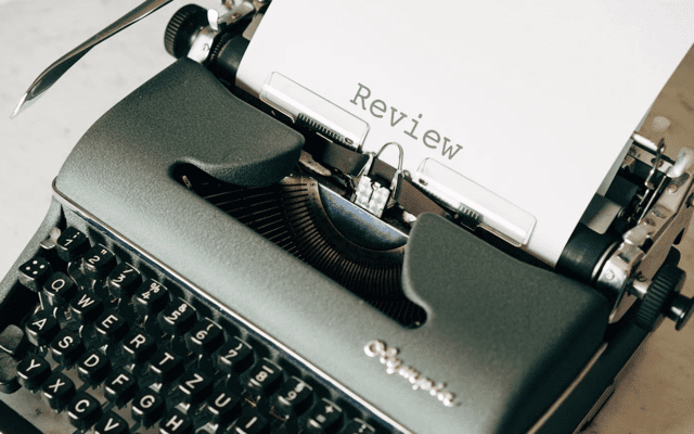 A black typewriter with the word review typed and centered.|