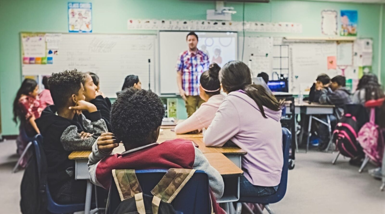 A public school classroom with a teacher speaking to students