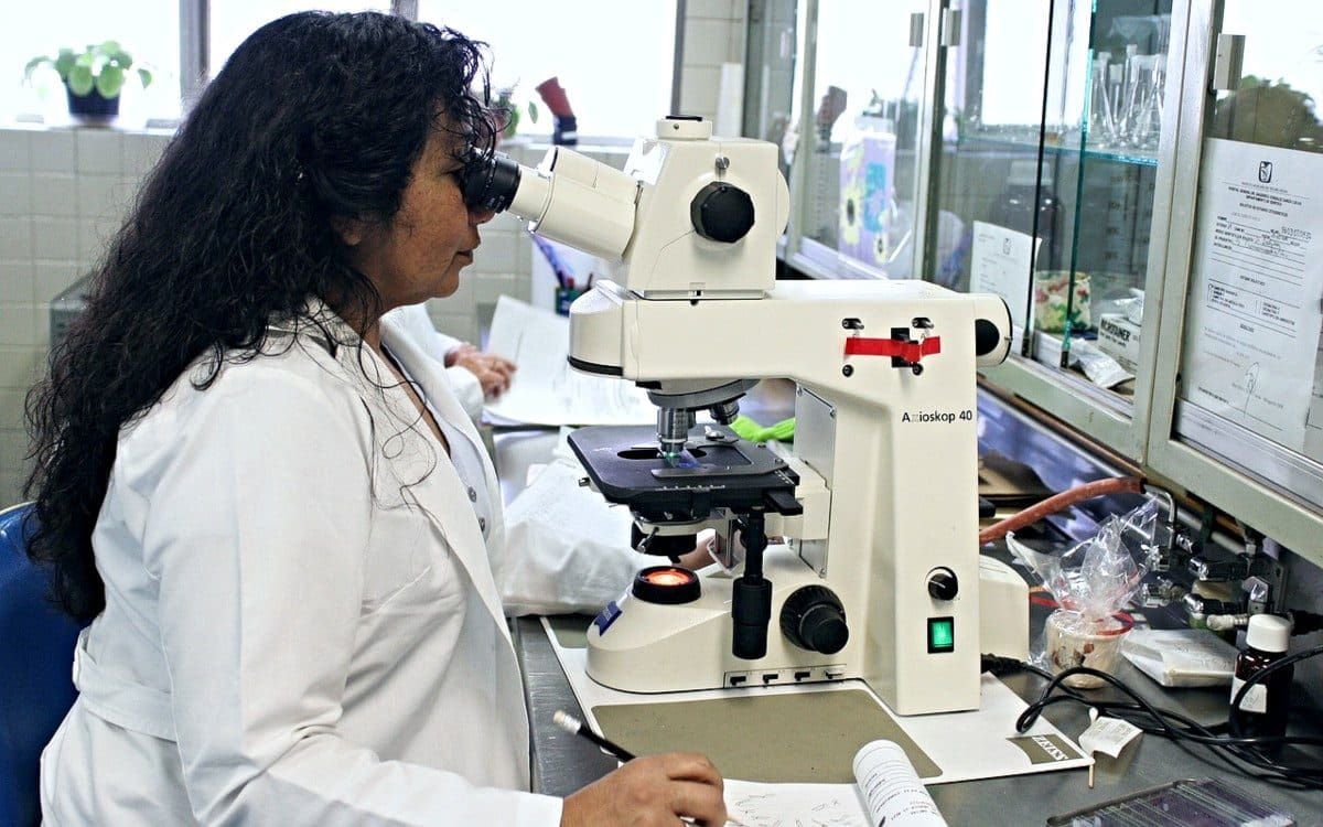 Scientist in lab looking into microscope